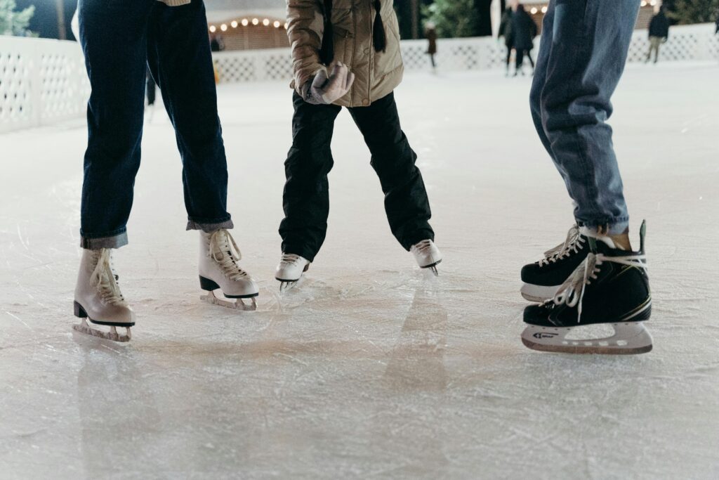 Group of people ice skating on a winter rink, showcasing leisure and enjoyment.