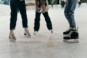 Group of people ice skating on a winter rink, showcasing leisure and enjoyment.